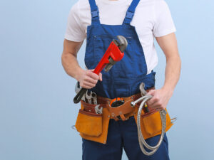 An image of a plumber with a tool belt and blue overalls