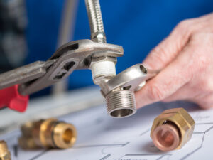 Image of a plumber screwing a plumb fitting on a pipe