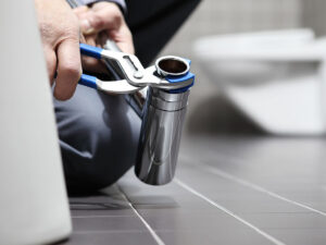 Image of a plumber working in a bathroom with a toilet in the background