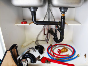 Image of plumbing tools and pipes underneath a sink