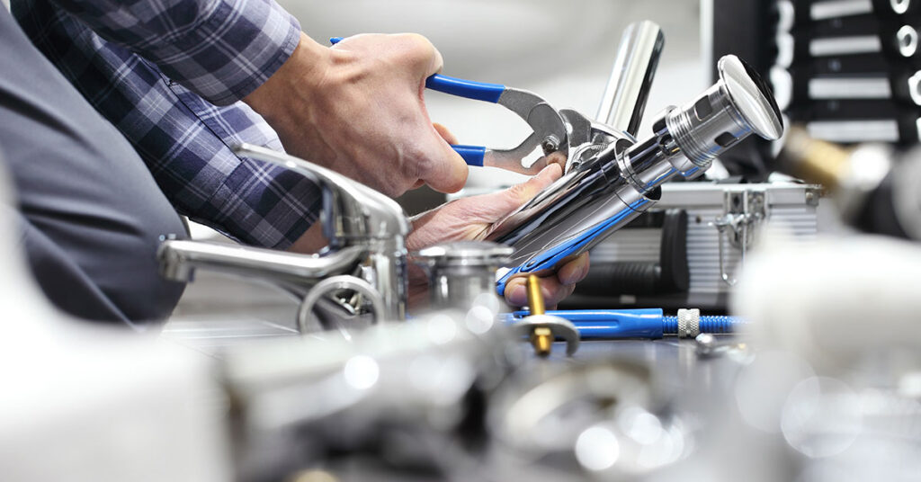 Closeup of plumber using tools to fix a plumbing issue