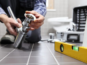 Plumber working on a pipe on the bathroom floor. 