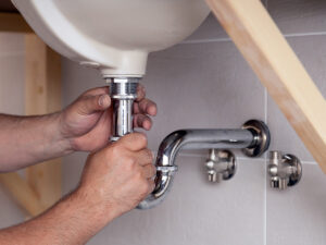 Plumbing working on the pipes under a sink. 