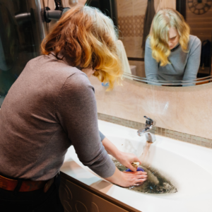 %Title% | Divine Woman trying to control overflowing water from a clogged pipe in a sink.