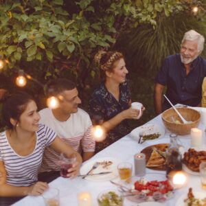 %Title% | Divine Family and friends enjoying dinner under string lights